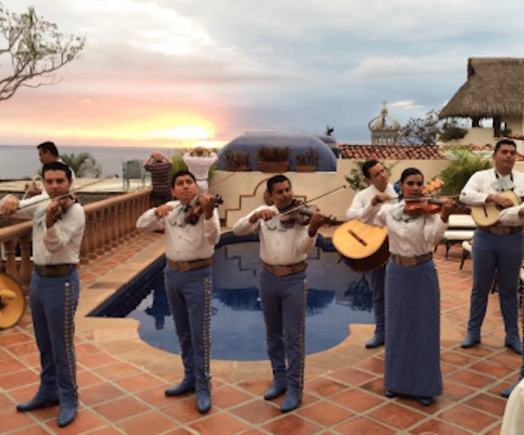A Mariachi band performing at the Hacienda San Angel Gourmet Restaurant against the backdrop of a beautiful sunset.