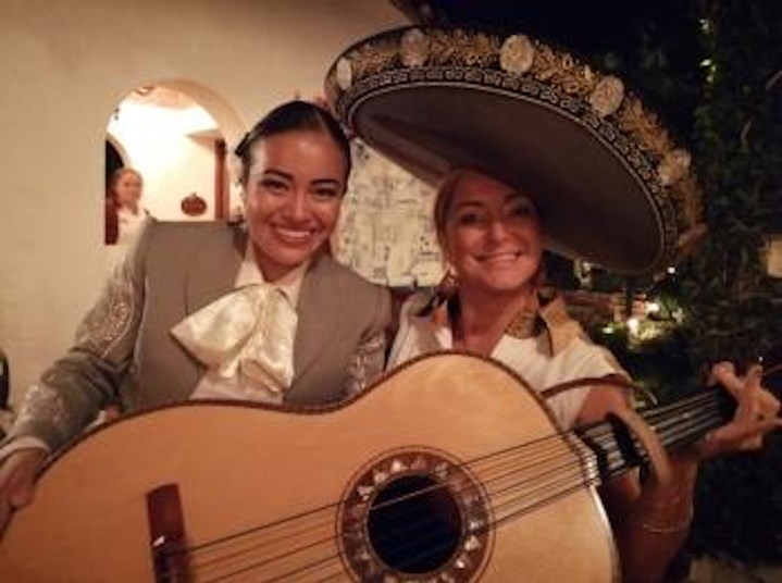 Mariachi ladies posing with sombrero and guitar.