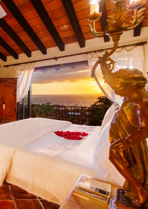 Honeymoon suite with rose petals in shape of a heart on the bed.