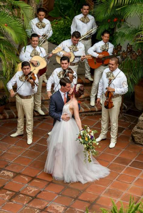 Married couple kissing in courtyard with a mariachi serenade.