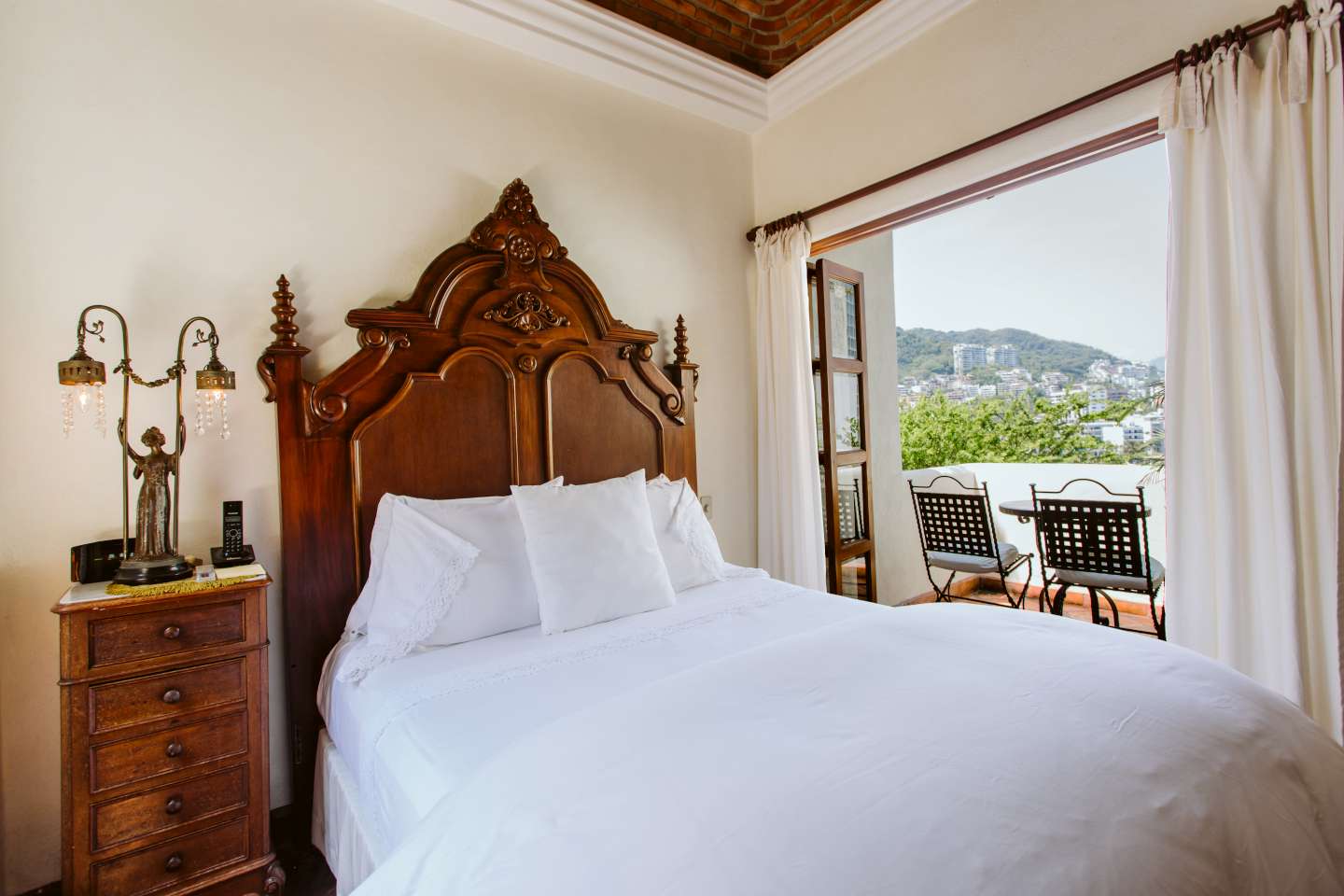 Angels Dome Suite showing its ornate wooden bed with white linen bedding and view of Sierra Madre Mountains
