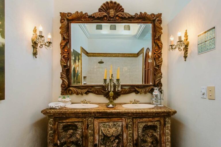 Lavatory's ornate wooden mirror and double sink vanity.