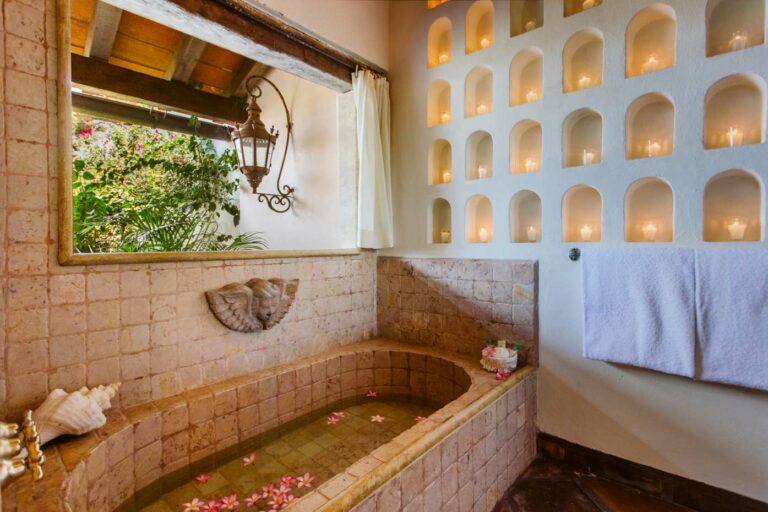 Bathroom shower and tub with wall of arches and candles in each arch. Flowers floating in the tub.