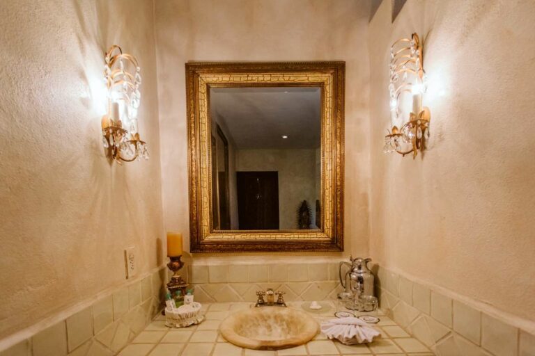 Lavatory with golden mirror over stone sink basin.