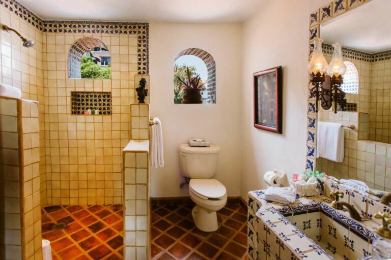 Washroom with white tile with blue sparrows around mirror and open shower.
