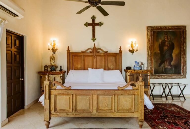 Rincon de Angeles Suite head on view of bed, nightstands and large antique religious painting to right of bed.