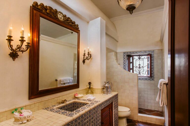 Bathroom with ornate wooden mirror and open shower.