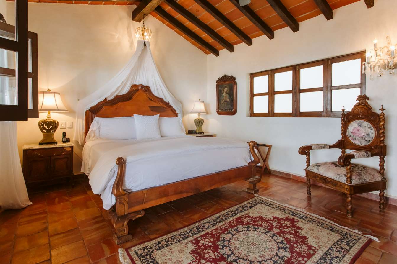 Vista de Santos Suite bed and large antique wooden chair.