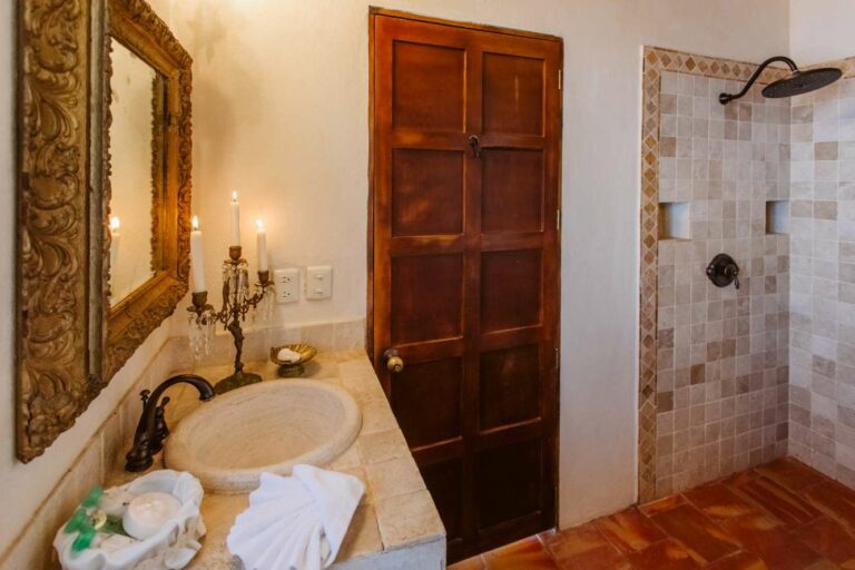 Lavatory with large wooden mirror over sink and open shower.