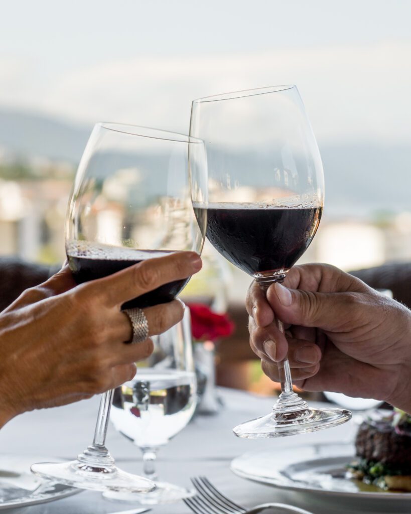 Close-up of a couple raising their wine glasses for a toast, with the scenic Sierra Madre Mountains in the background.